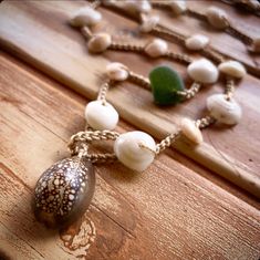 a close up of a necklace on a wooden surface with shells and beads hanging from it