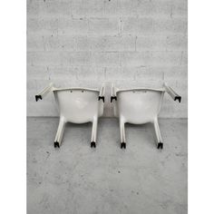 a pair of white chairs sitting next to each other on top of a cement floor