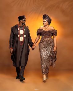 a man and woman dressed in african clothing holding hands while standing next to each other