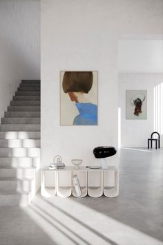 a white room with stairs and paintings on the wall