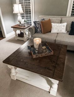 a living room with a couch, coffee table and two candles on the end tables