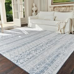 a white couch sitting next to a rug on top of a hard wood floor in a living room