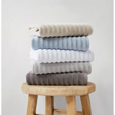 towels stacked on top of each other on a stool in front of a white wall