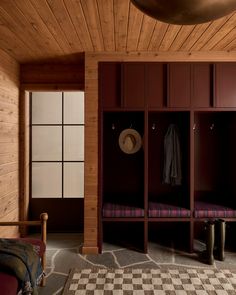 a room with wooden walls and flooring has a checkered rug on the floor