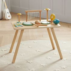 a child's wooden table with toys on it in a room next to a white rug