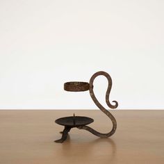 a metal object sitting on top of a wooden table next to a white wall and floor