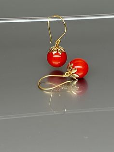 Gorgeous polished vibrant red coral globe earrings. The 12mm coral globes attached to beautiful 14K gold-filled flower caps as they dangle from the 14k gold-filled ear wires. The red globes are perfectly weighted while still being very comfortable to wear A truly gorgeous pair of earrings. *AAA coral spheres *Ball size (diameter): 12mm *Metal: 14K gold-filled *Earrings drop length: 31mm / 1.2 inch Solid gold, silver, and gemstones are also my materials of choice, I love working with these beauti Red Coral Dangle Jewelry For Gifts, Unique Red Coral Round Bead Jewelry, Gold Red Coral Round Jewelry, Elegant Red Coral Drop Earrings, Globe Earrings, Sphere Earrings, Red Stone Earrings, Red Coral Earrings, Ball Earrings