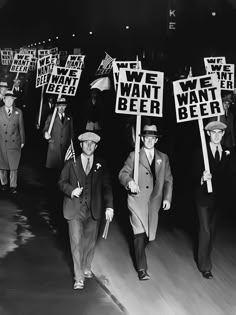 people walking down the street holding signs that read we want beer