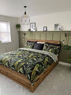 a bedroom with a bed, plant and pictures on the wall above it's headboard