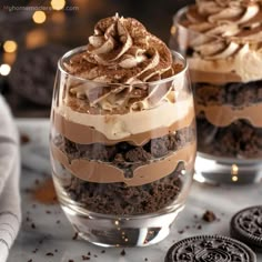 two glasses filled with desserts sitting on top of a table next to oreo cookies