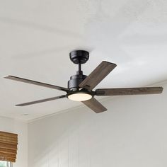 a ceiling fan in a room with white walls and wooden blinds on the windowsill