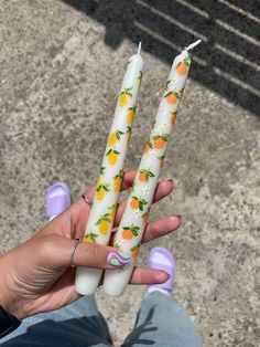 two white candles with lemons on them are being held by someone's hand