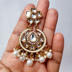 Adorn yourself in timeless splendor with our Beautiful Golden Chandbali Earrings embellished with Kundan and Zircon Stones, featuring suspended white pearl hangings. These earrings are a masterpiece of elegance, seamlessly blending traditional charm with contemporary design. The golden chandbali shape exudes regal allure, while the intricate detailing of Kundan and Zircon stones adds a touch of opulence. The ethereal white pearls suspended from the earrings create a graceful movement, making them a perfect choice for special occasions. Elevate your style with these exquisite earrings that embody sophistication and capture the essence of classic beauty. Materials: Brass, Pearl, Kundan & Zircon Stone ❋❋ Shipping Methods ❋❋ Standard Delivery - Take up to 8-14 business days (Worldwide). ❋❋ Ple White Hand Set Chandelier Earrings For Celebrations, White Chandbali Fusion Earrings, Festive Hand Set White Earrings, Festive White Hand Set Earrings, White Bridal Earrings For Festivals And Anniversary, White Bridal Earrings For Festivals And Anniversaries, Fusion Style White Earrings With Intricate Design, Fusion Style Bridal Earrings With Intricate Design In White, White Intricate Design Fusion Earrings