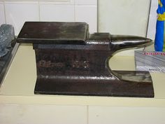 a metal object sitting on top of a counter next to a blue vase and some rocks