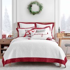 a white and red bed in a bedroom next to a christmas wreath on the wall