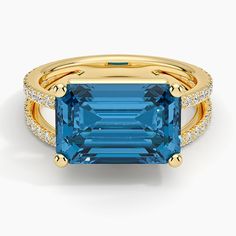 a gold ring with an aqua blue stone surrounded by white and yellow diamond accents on the band