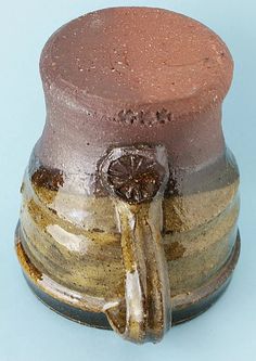 a brown and white vase with a handle on it's side, sitting on a blue surface