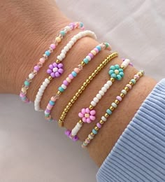 a woman's arm with four bracelets on it, one has flowers and the other has beads