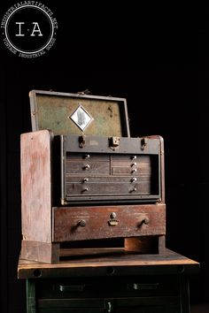 an old wooden chest sitting on top of a green table next to a black wall