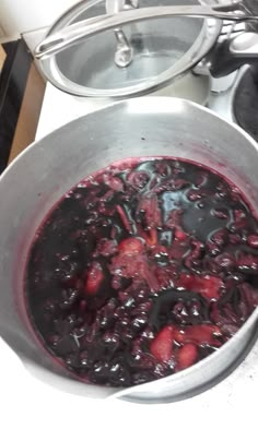 a pot full of food sitting on top of a stove next to a pan filled with fruit