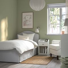 a bedroom with green walls, white furniture and a bed in the corner next to a window