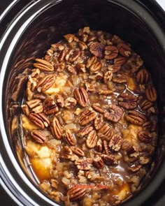 a crock pot filled with apples and pecans in the slow cooker, ready to be cooked