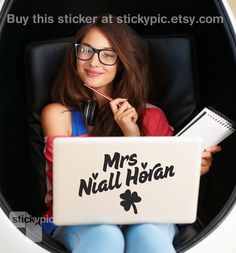 a woman sitting in a chair holding a laptop computer and listening to headphones with harry's official gravy taster sticker on it