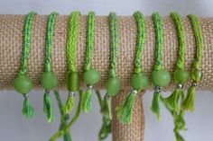 green beads and tassels are hanging on a piece of burlock