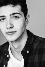 a black and white photo of a young man with short hair wearing a plaid shirt