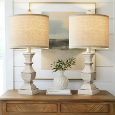 two lamps sitting on top of a wooden dresser