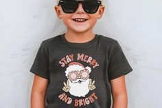 Stay Merry and Bright Santa Shirt, Christmas Toddler Tee, Merry Christmas Shirt, Fun Santa Shirt, Groovy Retro Santa Shirt, Christmas Shirt for Kids The Bella Canvas short sleeve tee for toddlers is a 100% Airlume combed and ring-spun cotton jersey with a tear-away label for extra comfort. Choose your favorite color out of a big variety, and make unique staples that toddlers will happily wear every day.  .: 100% airlume combed and ring-spun cotton (fiber content varies for different colors) .: Extra light fabric (3.9 oz/yd² (132 g/m .: Tear-away label Kids Christmas Tee Shirts, Boys Christmas Tshirt, Toddler Christmas Shirts Zazzle, Kids Gingerbread Shirt, Kids Chrismtas Shirt, Christmas Shirts For Kids, Santa Shirts, Merry Christmas Shirts, Toddler Christmas