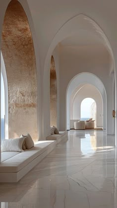 an arched hallway with white marble flooring and large windows on either side of the room