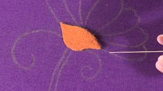 someone is using a needle to thread the fabric on top of an orange piece of material