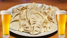 a plate with dumplings and two mugs of beer sitting on a wooden table