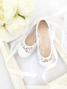 a pair of white shoes sitting on top of a table next to a bouquet of flowers