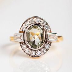 Reminiscent of art deco, this stunning ring by Carrie Elizabeth features a glowing green amethyst surrounded by shimmering cubic zirconia. Shop more vintage inspired rings at Local Eclectic. Amethyst Diamond Ring With Rose Cut Diamonds For Anniversary, Art Deco Amethyst Ring For Anniversary, Art Deco Oval Amethyst Ring, Art Deco Oval Diamond Ring With Accent Stones, Luxury Green Amethyst Ring For Anniversary, Fine Jewelry Green Amethyst Ring With Center Stone, Green Amethyst Ring With Center Stone, Eclectic Engagement Rings, Green Ring Vintage