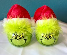 two green balls with yellow and red hair on them, one has a grin face painted on it