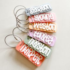 Kids Backpack or Lunchbox Tag : . : . : ITEM DETAILS : . : . : Tag is approx. 3.5" wide. Name will be in white acrylic in the font shown. Select one color for the background of the tag. In the personalization box, please leave the name you would like on the tag. Comes with a cable wire keyring.  Laser cut from acrylic. IMPORTANT: These bag tags are made from acrylic, which is a hard plastic. Please handle with care. If dropped or banged against a hard surface, they most likely will break. We are Shrink Plastic Name Tags, Cricut Bag Tag Baby, Cricut Tags Bags Boxes And More, Rectangular Travel Bag With Keychain, Trendy Pink Travel Keychain, Customized Rectangular Keychains For School, Multicolor Rectangular Keychains For Travel, Customizable Rectangular Keychain For Everyday Use, Trendy Rectangular Keychains For Gifts