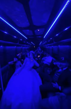 a bride and groom are sitting in the back of a bus with blue lights on