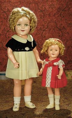 two dolls standing next to each other holding hands