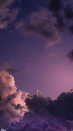 an airplane is flying in the sky with purple clouds