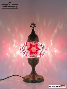 a red and white lamp sitting on top of a table next to a pink wall