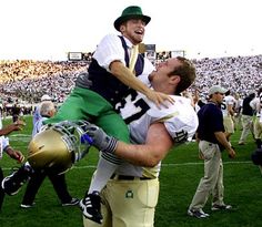 a football player is being carried on his shoulders by another man in the middle of a crowded stadium