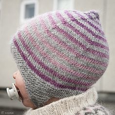 a close up of a person wearing a knitted hat with ear phones on their ears