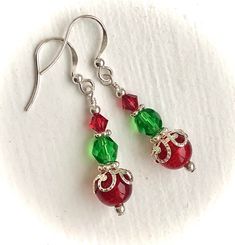 Holiday Christmas Silver Red and Green Dangle Earrings: These festive Christmas/Holiday red and green dangle earrings are made with sterling silver components, round, red crackle glass beads topped with ornamental silver bead caps, green faceted oval beads and red Swarovski crystals. Each earring is carefully wire wrapped and attached to sterling silver French hook ear wires.  Perfect for Christmas gatherings or everyday Holiday wear. Also ideal for a Christmas stocking stuffer, sister gift, dau Christmas Celebration Jewelry Drop Earrings, Holiday Jewelry With Matching Earrings, Christmas Celebration Drop Earrings Jewelry, Red Jewelry For Christmas Celebration, Red Jewelry For Holiday Jewelry Making, Holiday Dangle Earrings With Ear Wire, Red Jewelry For Christmas Holiday, Festive Christmas Jewelry With Matching Earrings, Christmas Celebration Dangle Earrings