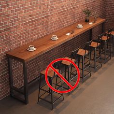 a row of bar stools sitting in front of a brick wall with a no sign over them