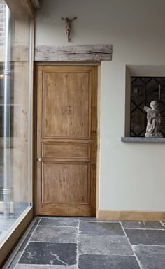 a wooden door sitting next to a window on top of a stone floor covered in tile