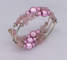 An eye catching bracelet made with pink quartz gemstones, pink Miracle beads and silver plated spacers. Rose Quartz is a symbol of unconditional love and is therefore  a perfect gift for Valentines day or for a wedding anniversary.  It is also supposed to help attract love and partnerships and therefore perfect if you are seeking a new relationship or as a gift for a friend. Miracle beads are acrylic, high gloss colourful beads with a mirror core.  As a result they 'glow' when they catch the light!  This bracelet uses  10mm and 6mm size beads. The bracelet is made with 2 strands of memory wire and will fit most wrists. Finished with a silver plated puffed heart and pink quartz charm.  Presented in an organza bag. A matching necklace and earrings are available - please ask for a custom orde Pink Spiritual Bangle, Handmade Pink Crystal Bracelet For Wedding, Elegant Rose Quartz Pink Crystal Bracelet, Pink Crystal Bracelet With Round Beads For Party, Silver Beaded Rose Quartz Bracelets, Elegant Pink Wire Wrapped Bracelets, Pink Hand Wrapped Round Bead Jewelry, Pink Rose Quartz Round Stretch Bracelet, Hand Wrapped Pink Round Bead Jewelry