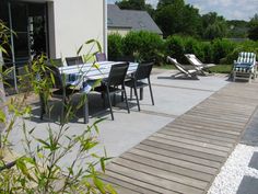 a table and chairs on a patio next to a wooden deck with gravel in the foreground