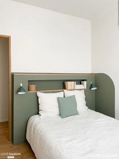 a white bed sitting in a bedroom next to a green headboard on a wall